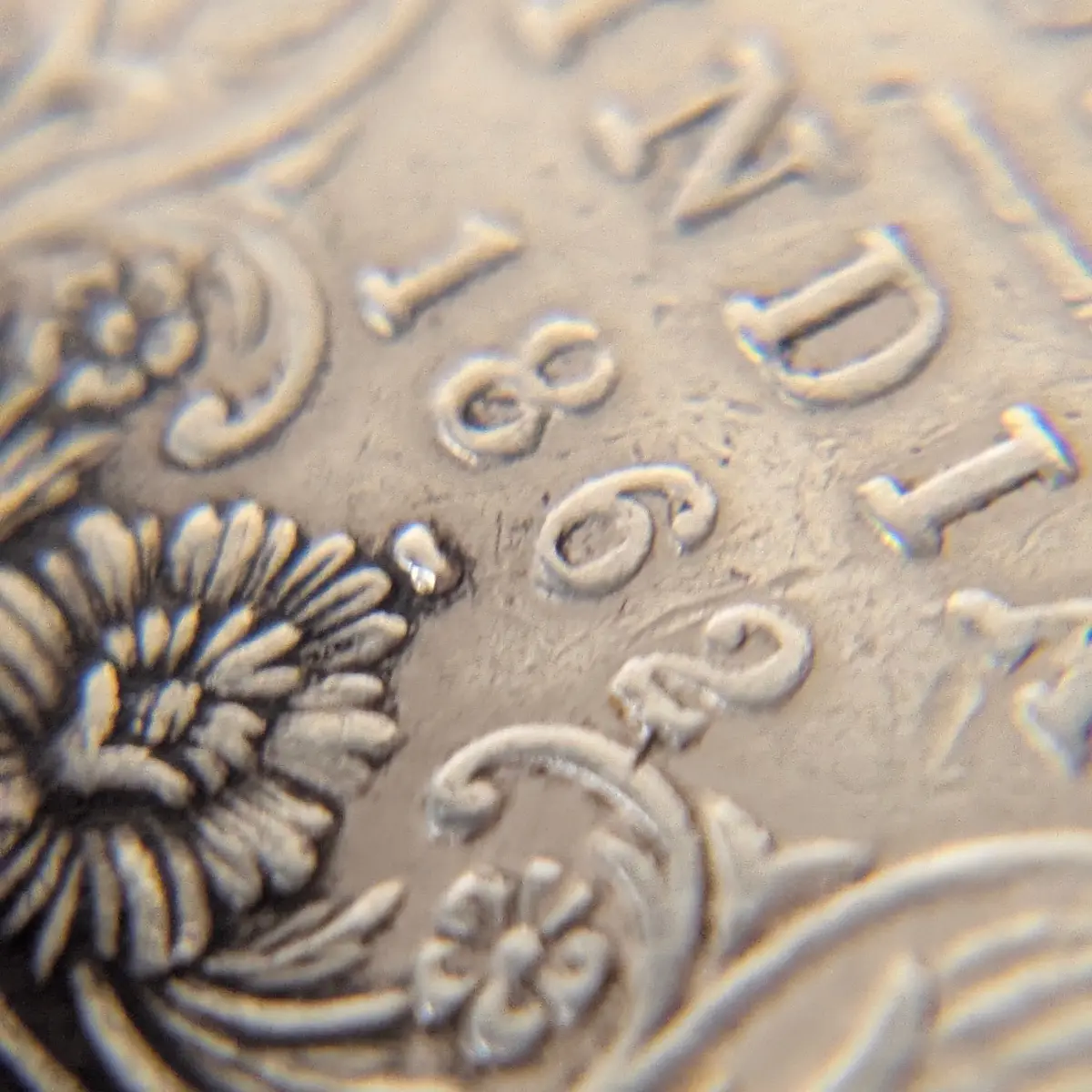 Macro close-up of the “1862” date on a British India One Rupee silver coin with floral artwork.