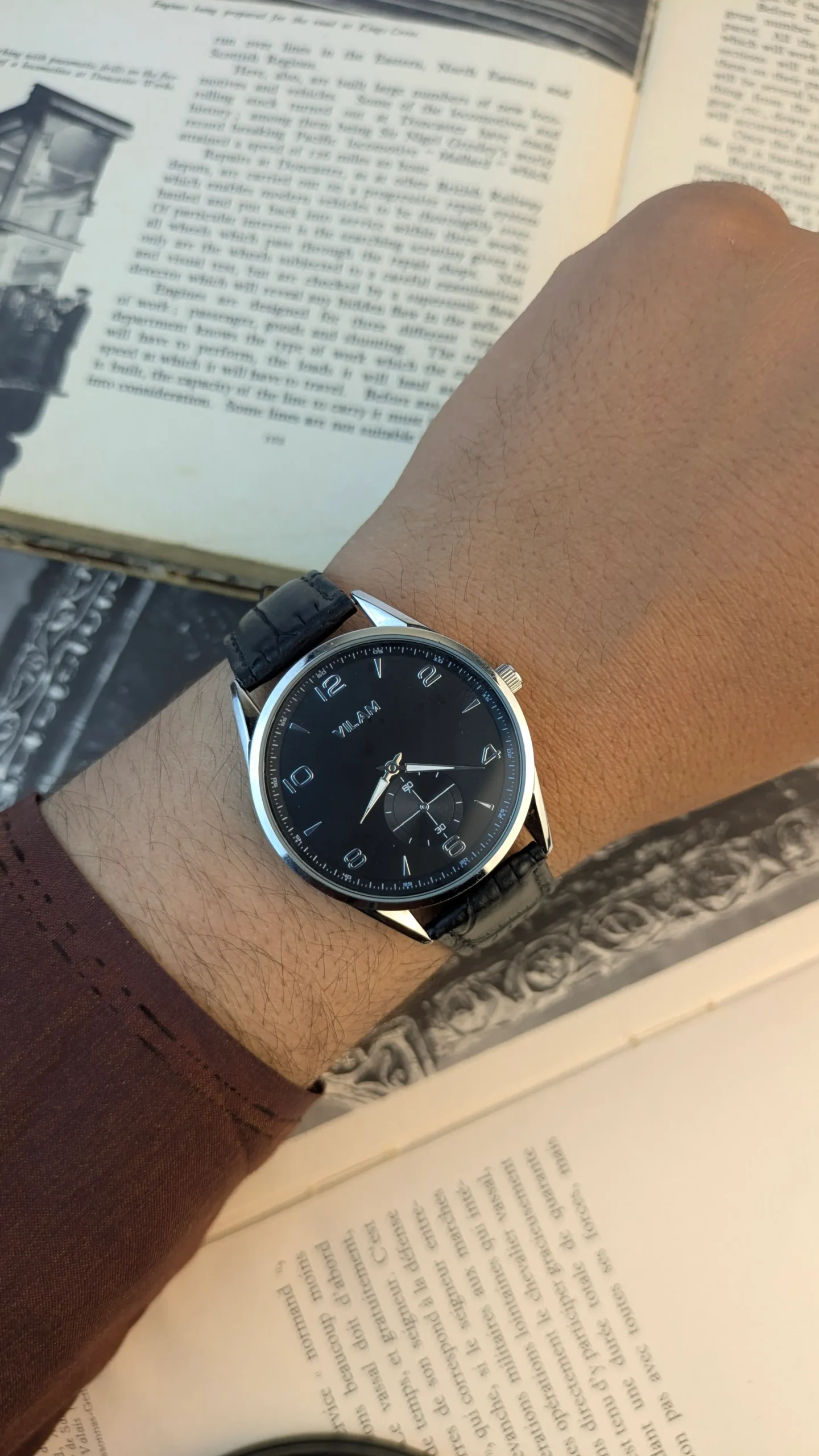 Vilam 40mm silver tone round case dress watch with matte black dial and black croco embossed leather strap held in hand