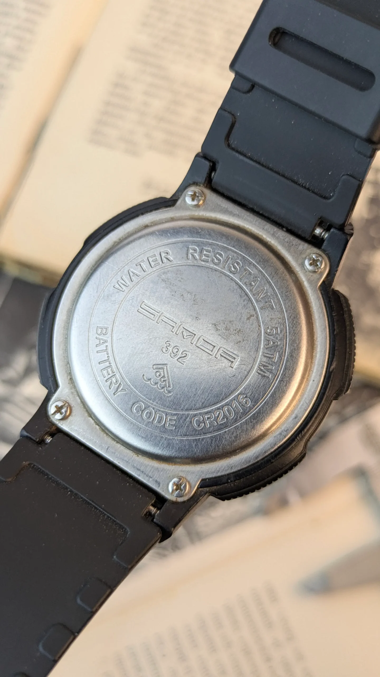 Back case of Sanda digital sports watch showing stainless steel screw back and water resistant markings