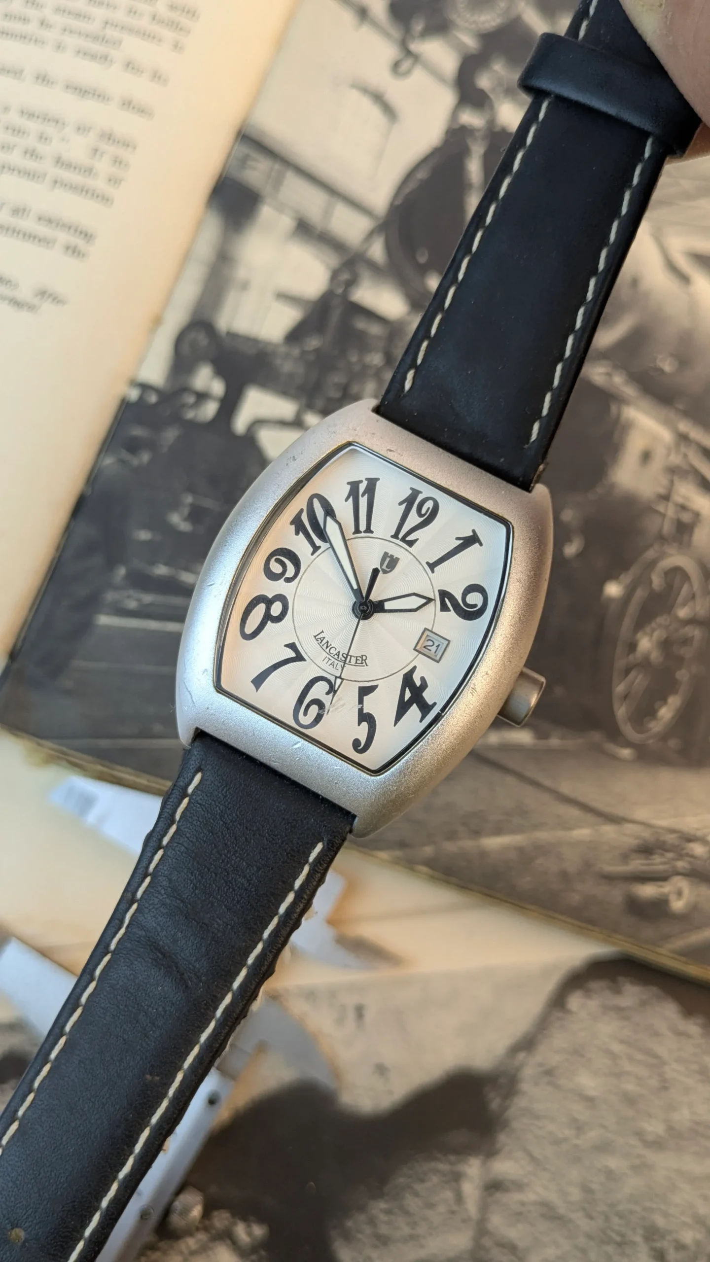 Close-up of Lancaster Italy curved silver dial watch with date display and artistic numeral design