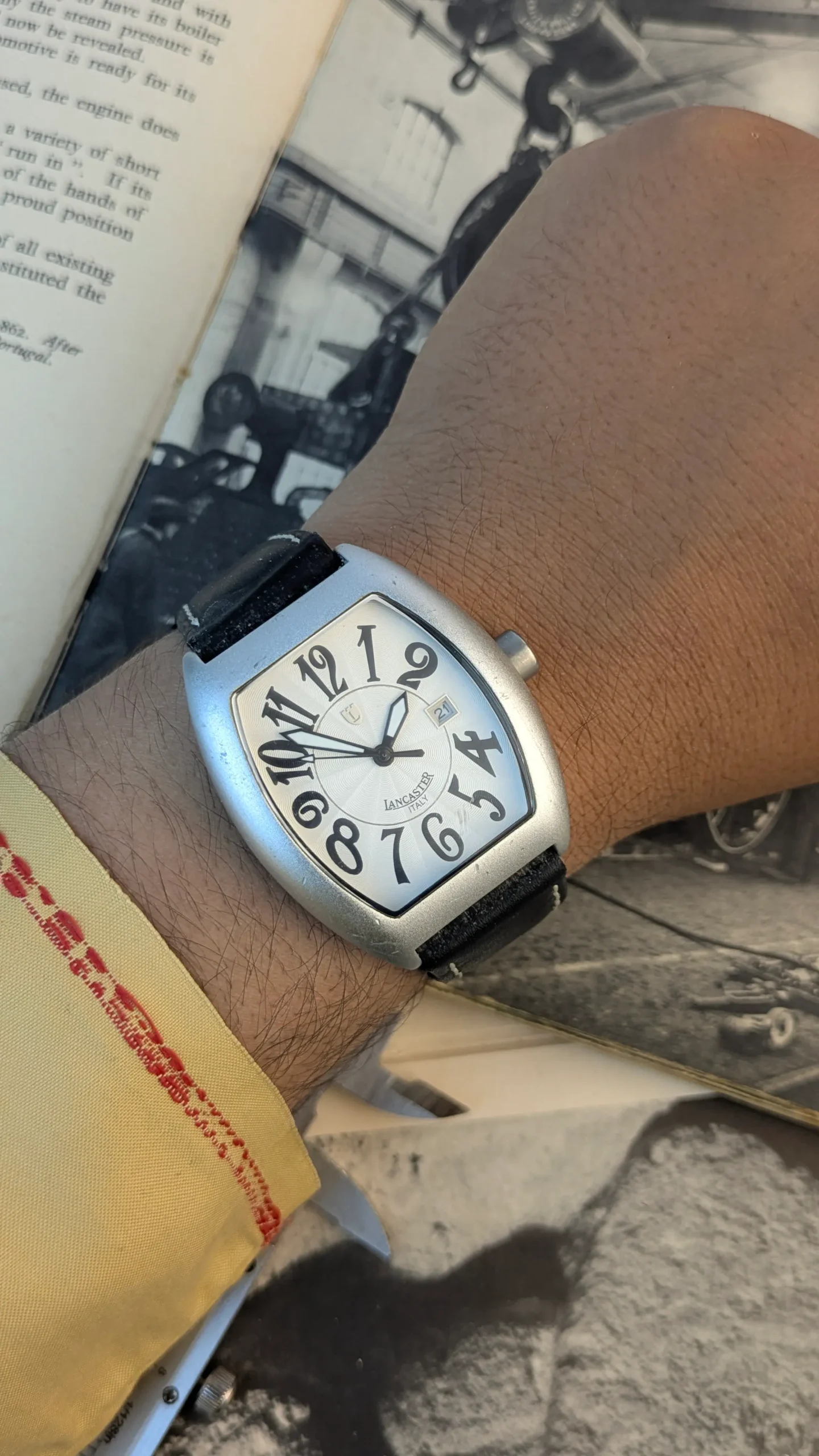 Lancaster Italy curved tonneau watch worn on wrist with black leather strap and silver designer dial