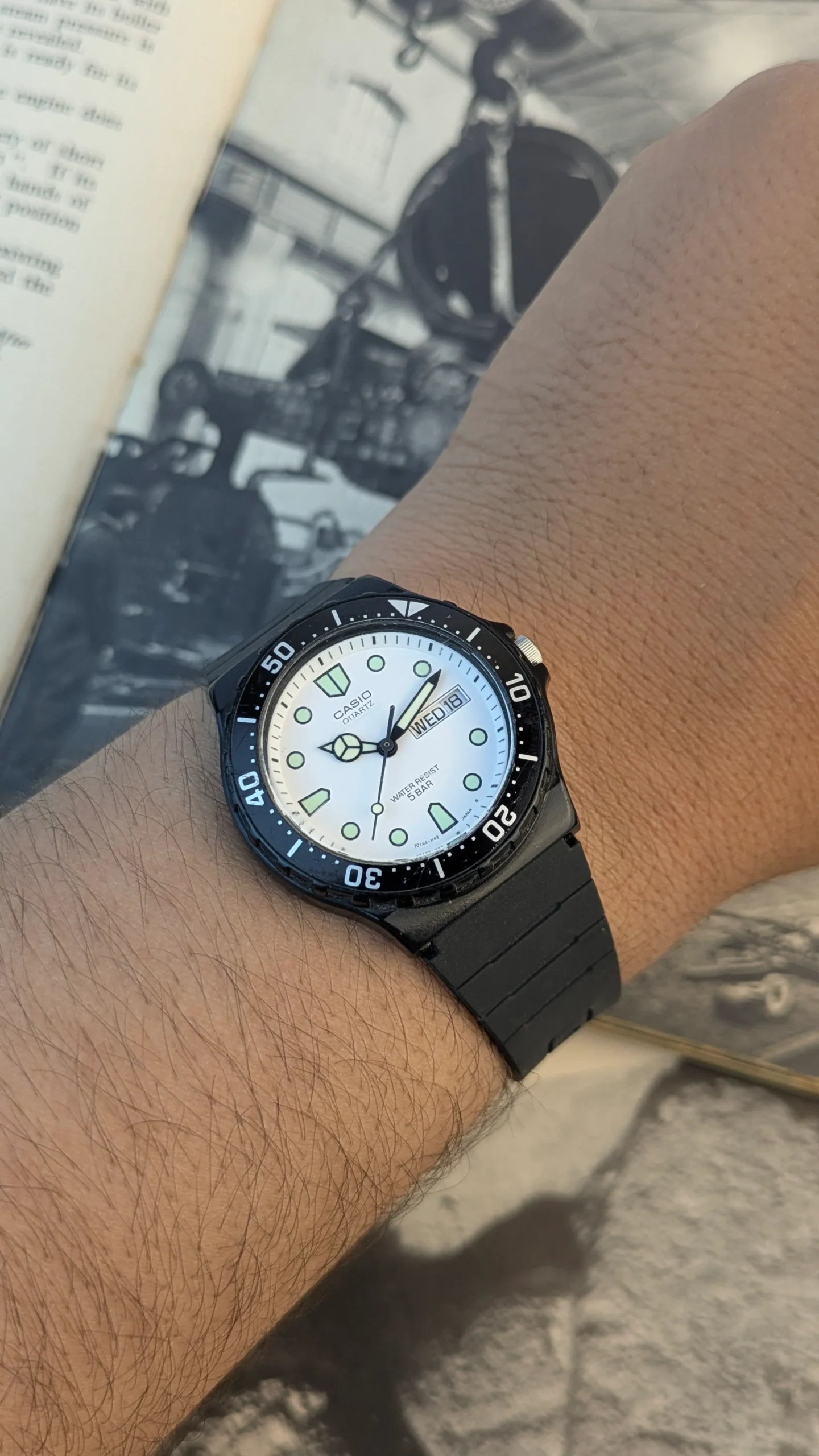 Close-up of Casio MRW-200H white dial with day-date display and luminous-style markers.